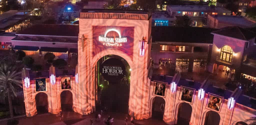 A large illuminated Halloween Horror Nights entrance with arches and artwork displays at night.