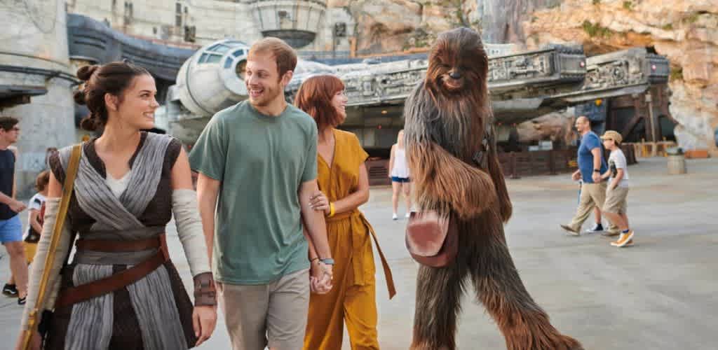 People walking and smiling with Chewbacca character from Star Wars in an amusement park setting