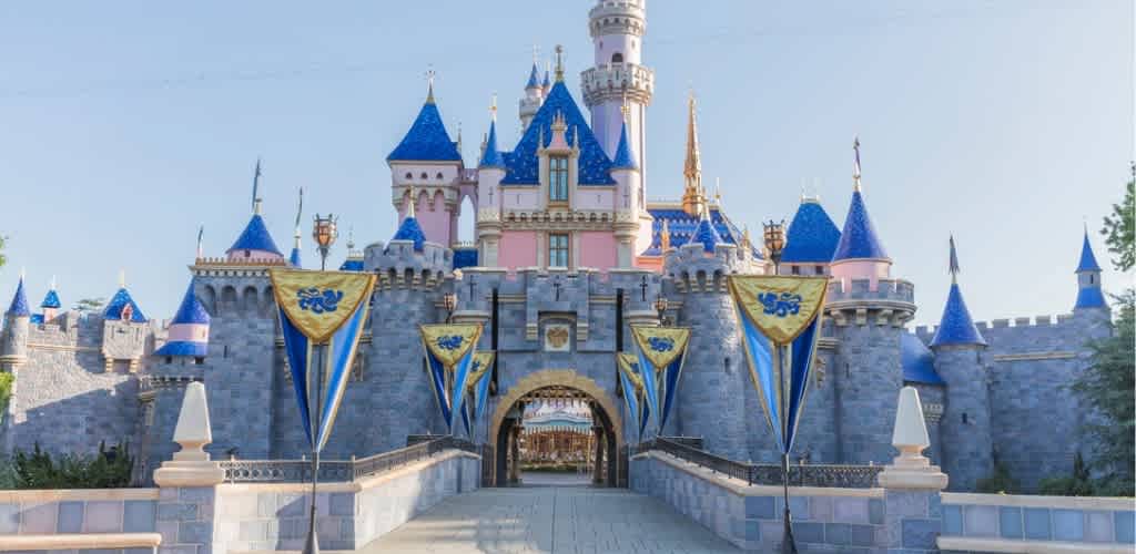 A colorful medieval castle with blue turrets and pink accents under a clear sky at Disneyland California.