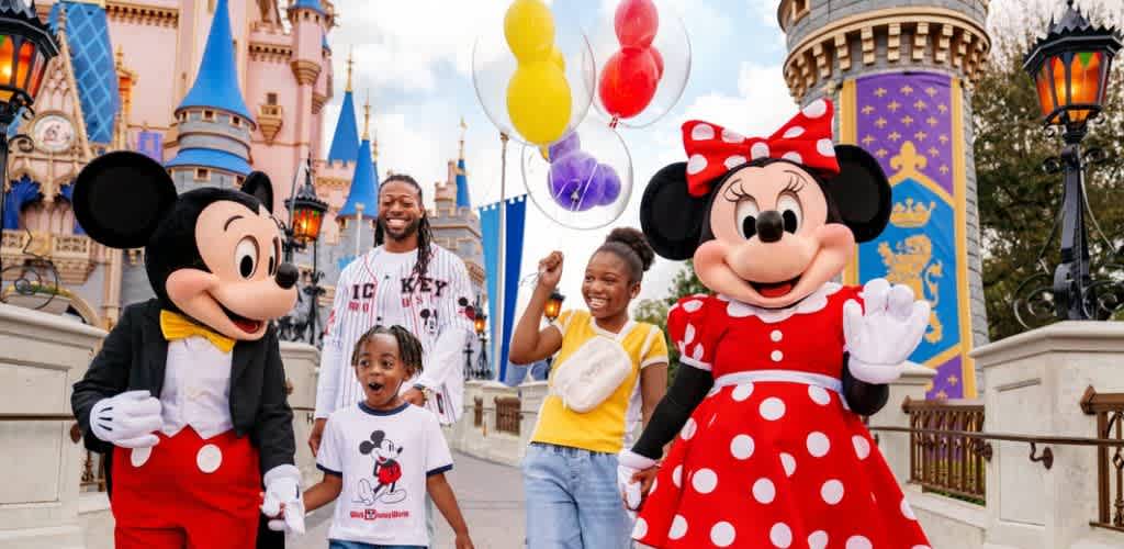 People in costumes with Mickey Mouse and Minnie Mouse at Disneyland with children on a themed castle background