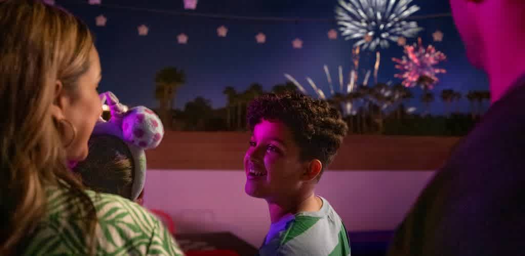 Group of friends enjoying fireworks celebration outdoors at night with colorful sky and palm trees in the background
