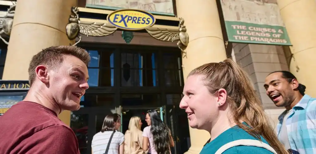 Group of smiling people standing outside an arcade or entertainment venue at the entrance