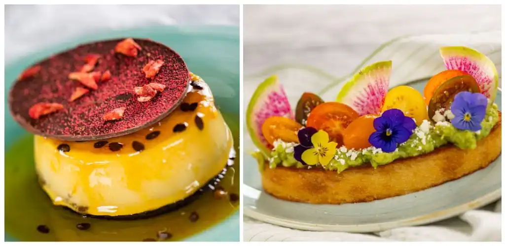 A dessert with a glossy yellow glaze topped with a red chocolate disk and small pink decorations, alongside a fruit-topped pastry with colorful edible flowers and sliced fruits.