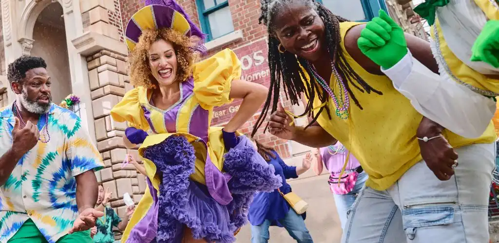 Guests having fun with a Mardi Gras performer in a colorful costume at Universal Orlando Resort.