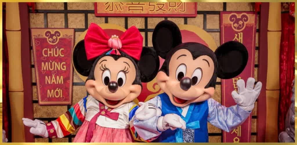 Costumed Mickey and Minnie Mouse characters waving in front of festive Asian-themed decorations with red banners and gold accents