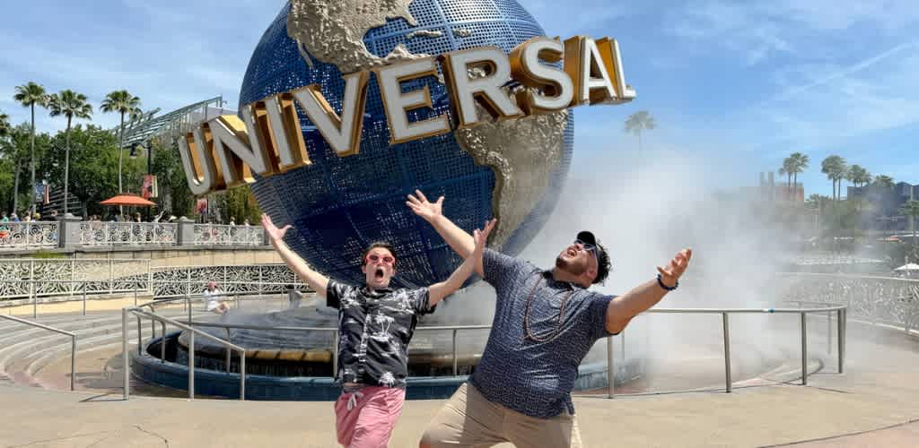 Two people posing happily in front of the Universal Studios globe at the entrance