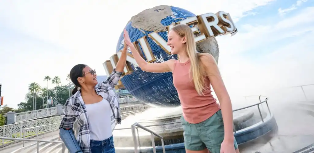 Two young ladies high-fiving each other near the Universal Orlando globe.