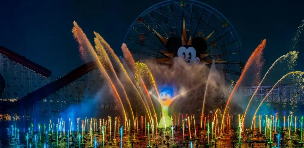 Disneyland's illuminated water fountains create a vibrant display against the night sky.