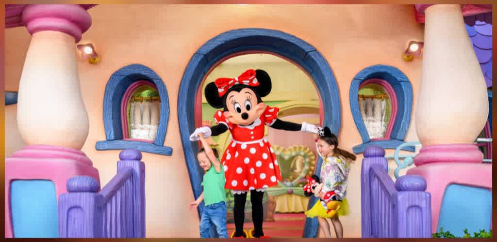 Children interacting with Minnie Mouse in a colorful Disney themed setting with pastel walls and whimsical architecture