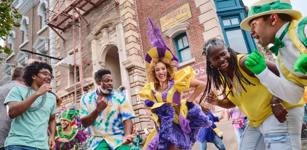 People celebrating Mardi Gras parade dancing and having fun in colorful costumes on city street