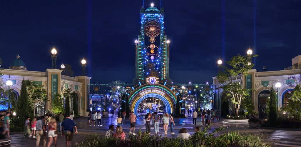 A nighttime scene at an amusement park entrance with bright colorful lights, an archway, and people walking towards the rides and attractions.