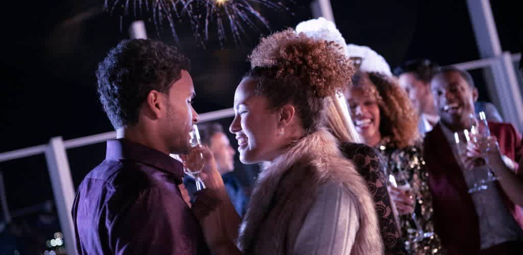 Group of people smiling and talking at a celebration or party with drinks, enjoying social interaction and fun evening together.