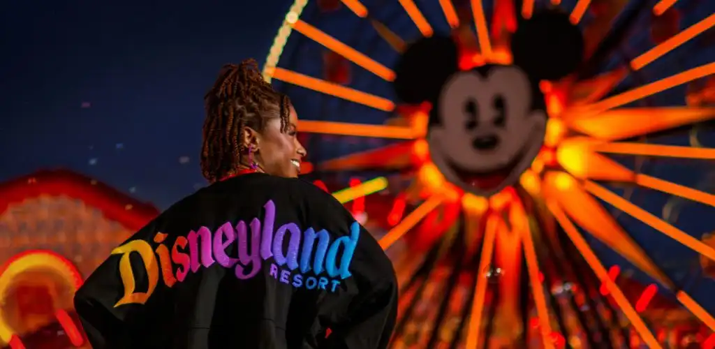 A smiling woman with a backpack stands in front of a colorful balloon, radiating joy and adventure.