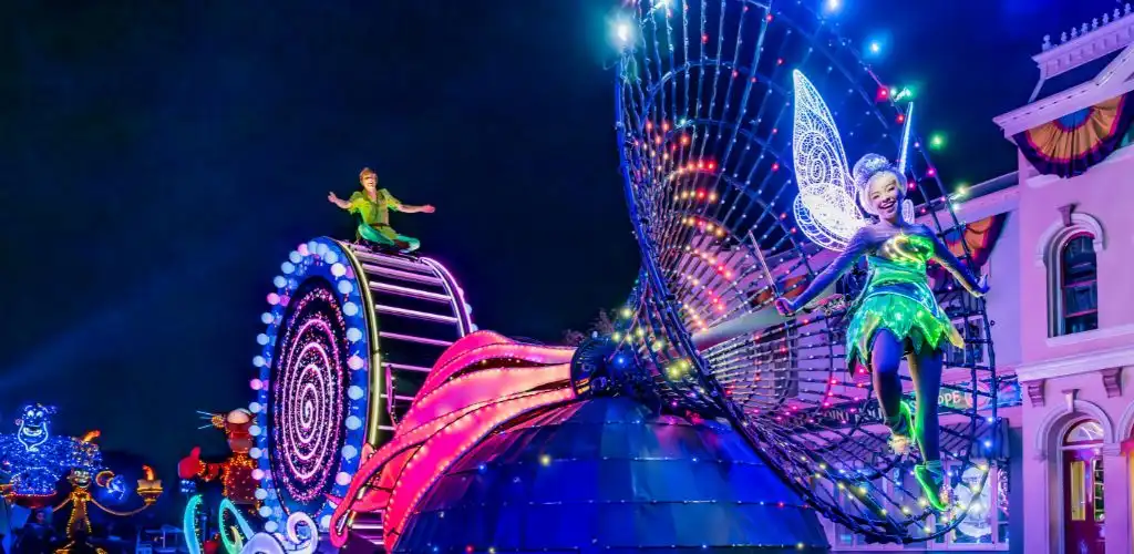 Colorful lights illuminate Disneyland parades at night, creating a vibrant and festive atmosphere for attendees.