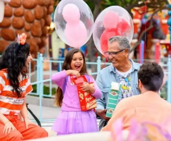 Children and adults happily enjoying cotton candy and balloons at an amusement park or fair outdoor setting
