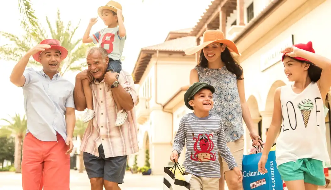 A joyful family strolls through a Disney shopping district, carrying bags filled with magical finds while enjoying a sunny day of retail therapy.