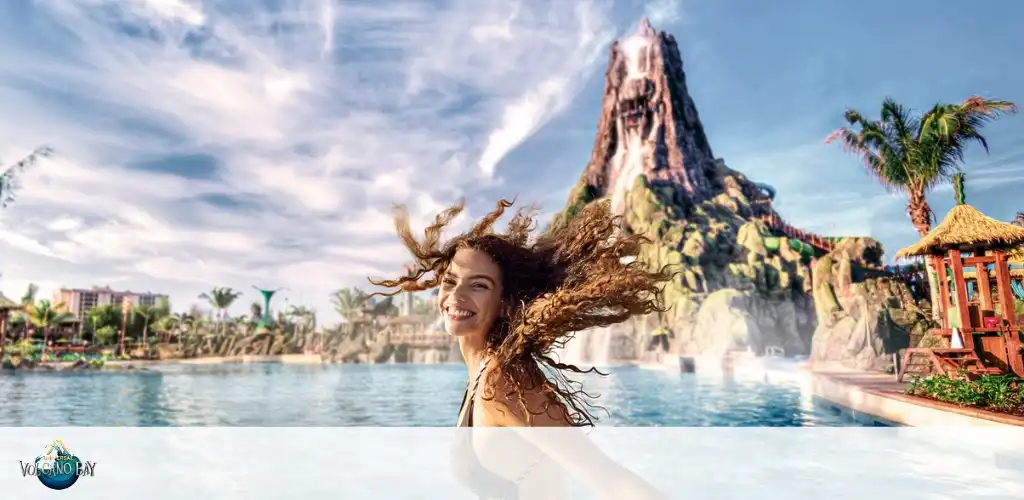 Smiling guest enjoying the crystal-clear waters at Universal’s Volcano Bay, with the towering Krakatau volcano and tropical scenery in the background.
