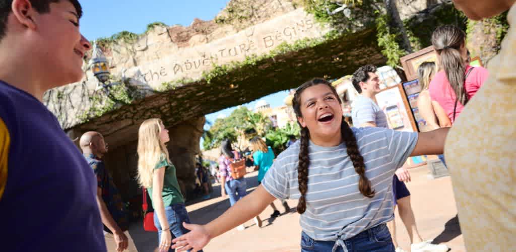 Excited guest welcoming friends under the 'The Adventure Begins' arch at Universal’s Islands of Adventure, ready for an action-packed day of thrills and exploration.