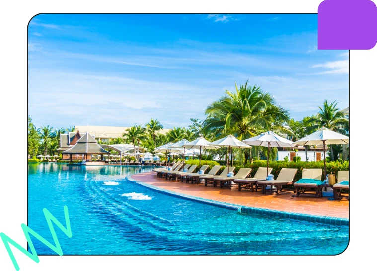 A luxurious outdoor pool area with lounge chairs, umbrellas, palm trees, and a clear blue sky, perfect for relaxation and leisure.